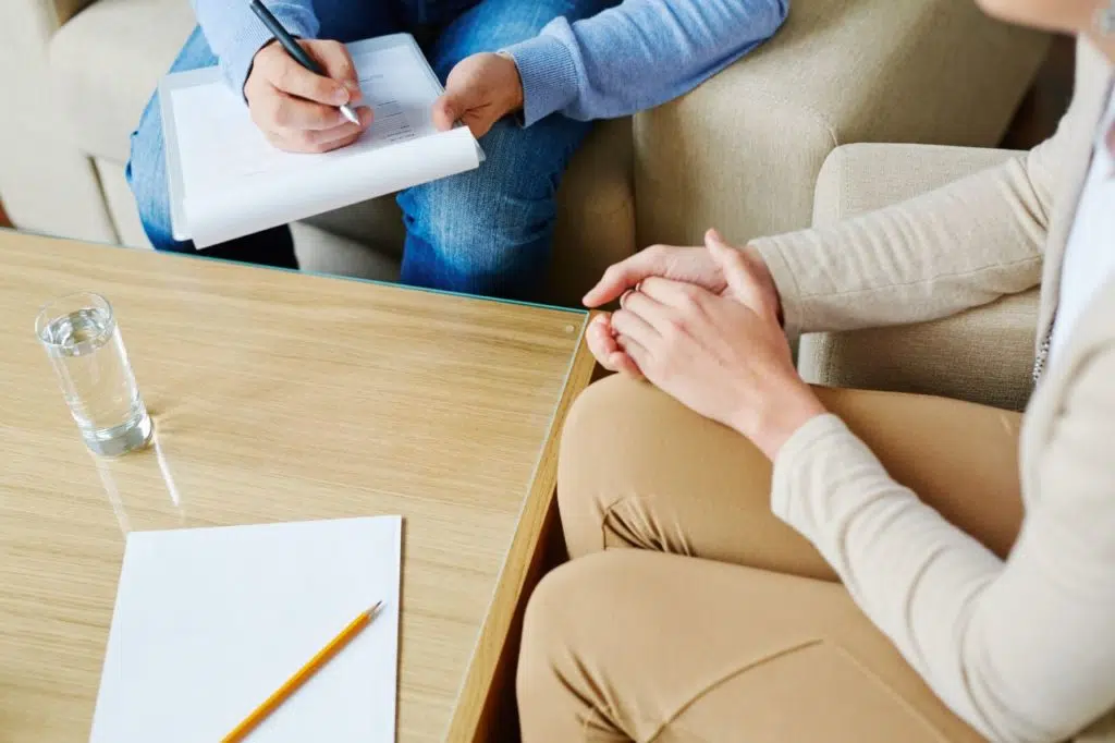 Psychologue prenant des notes pendant une séance de consultation avec un patient.