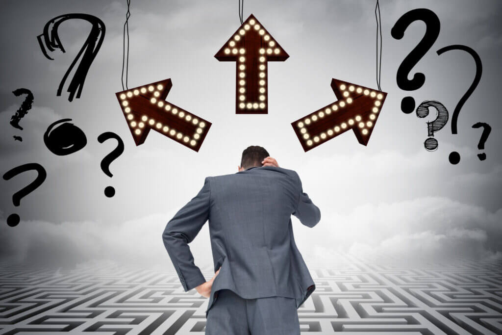 Recherche d'hypothèses mémoire. Homme pensif face à des flèches et points d'interrogation, symbolisant l'exploration de pistes pour la rédaction académique.