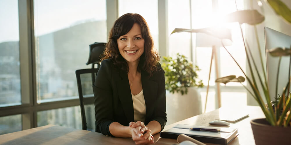 Experte en accompagnement académique souriante dans un bureau moderne, illustrant le conseil et l’accompagnement pour la rédaction de mémoire universitaire.