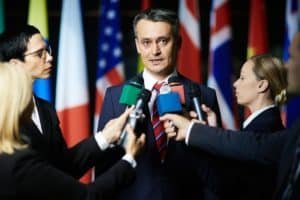 Homme politique s'exprimant devant des micros et des drapeaux, illustration d'un mémoire de Science Politique accompagné par Expertmemoire