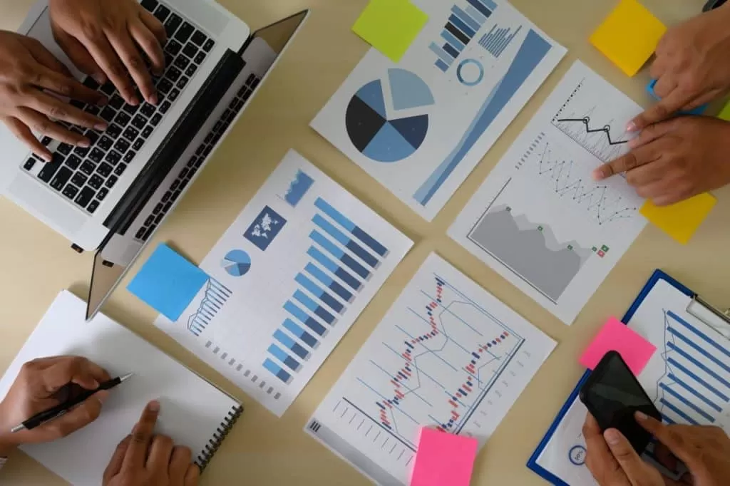 Réunion d’équipe autour d’un ordinateur portable avec rapports, graphiques et tableaux d’analyse de performance