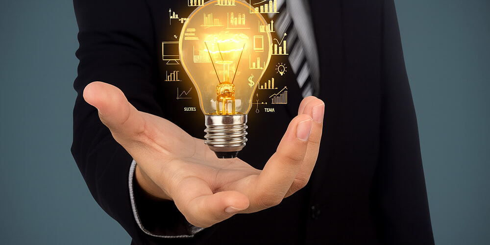 Homme d’affaires en costume tenant une ampoule lumineuse holographique représentant des idées, graphiques et innovations.