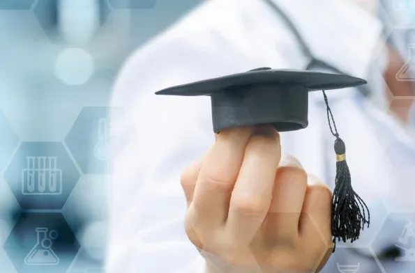 Aide à la rédaction de votre thèse Étudiant tenant un chapeau de diplômé, symbole de la réussite de la rédaction d'une thèse